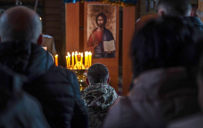 _viyskoviy_molitsya_pri_svichkah_pered_ikonoyu_lyudi_rozmiti_gettyimages_2191457460_af56fb250aed1e0d60bdbd62d28ef592_1300x820