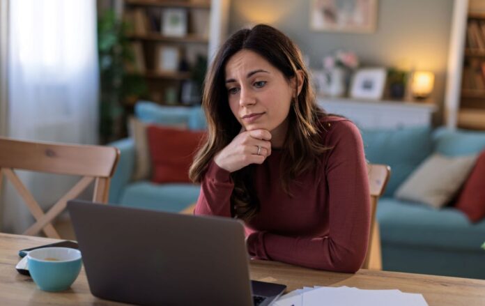_zhinka_divitsya_v_ekran_borodova_koftina_zamislena_zdivuvannya_blakitna_chashka_na_stoli_robota_frilans_gettyimages_2206686118_192fe67ae4f5607fd7b5fab7c1a5102f_1300x820