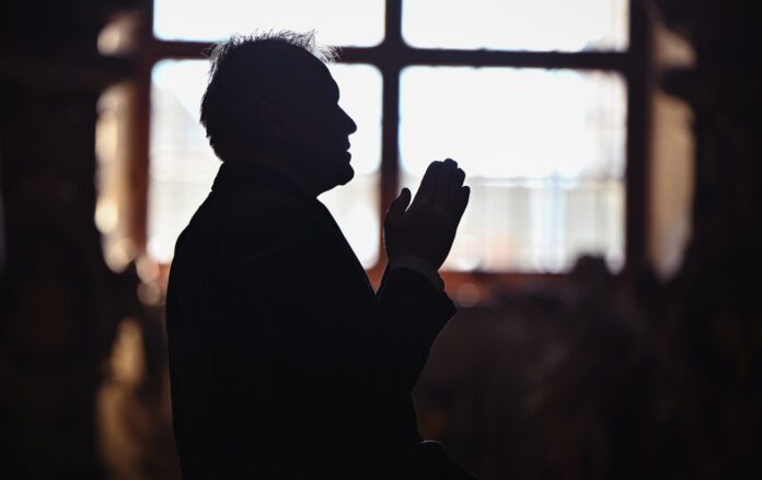 _cholovik_molitsya_proti_vikna_hram_molitva_bazhannya_gettyimages_2151577649_18fc5cd09b57ead842225ee1e7e3295e_1300x820