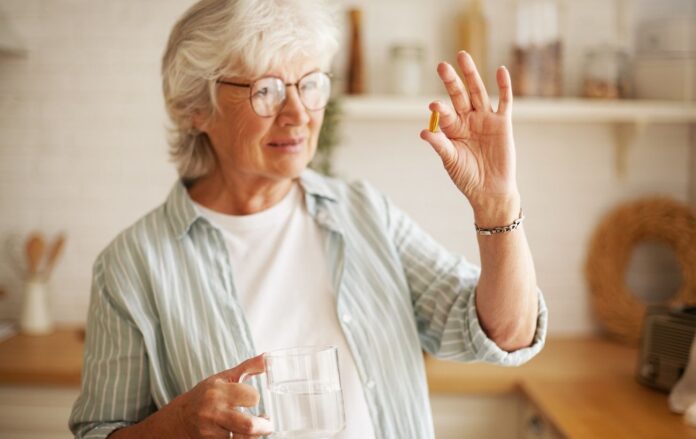 beautiful_mature_sixty_year_old_female_stylish_eyeglasses_holding_mug_omega_3_supplement_capsule_going_take_vitamin_after_meal_senior_gray_haired_woman_taking_fish_oil_pill_with_water_bb052623db201ae786323a6607ff5588_1300x820